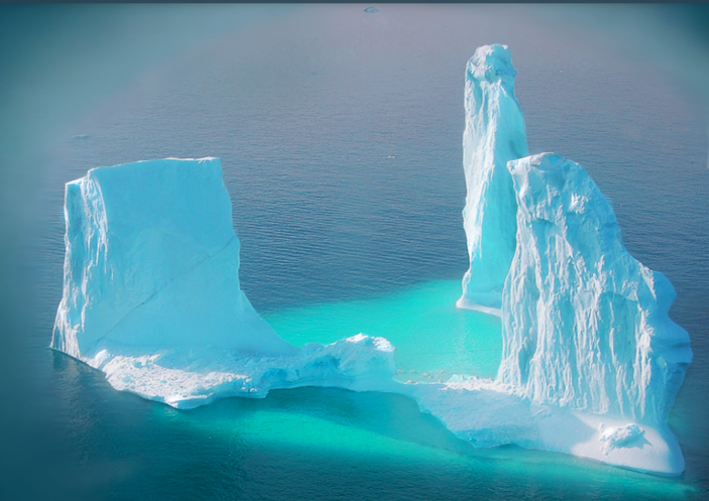 Two icebergs tower above a blue ocean.